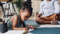 Close up shot of happy young African American girl and a boy using coloured pencils drawing on a floor. Close up shot of happy young African American girl and a boy using coloured pencils drawing on a floor.