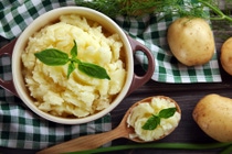 Mashed potatoes in bowl on wooden table with checkered napkin
