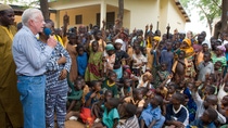 February 8, 2007. Savelugu Hospital, Northern Province, Ghana. President Jimmy Carter and his wife Rosalynn address Savelugu children on the seriousness of eradicating guinea worm disease. In this photo he has said "Hands up all those who have had Guinea Worm" and many of the children put up their hands.