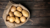 Sack of fresh raw potatoes on wooden background, top view; Shutterstock ID 1018491535; purchase_order:Bestelling ; job:; client:; other: