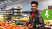 A man selecting fresh tomatoes in a grocery store. 