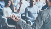 Business coach. Rear view of man gesturing with hand while standing against defocused group of people sitting at the chairs in front of him ; Shutterstock ID 439214011; Jobnummer: 02200; Projekt: Präsentation; Endkunde: BASF SE, G-EVO/EB, Frau Sauer; Sonstiges: BASF SE, ESI/K Matthias Baque Business coach. Rear view of man gesturing with hand while standing against defocused group of people sitting at the chairs in front of him ; Shutterstock ID 439214011; Jobnummer: 02200; Projekt: Präsentation; Endkunde: BASF SE, G-EVO/EB, Frau Sauer; Sonstiges: BASF SE, ESI/K Matthias Baque