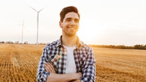 Happy man standing against the industrial landscape with wind turbines Happy man standing against the industrial landscape with wind turbines