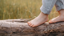 Child balancing on a trunk lying in front of a field