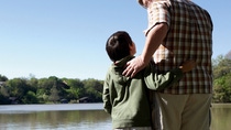 Man and boy standing at a lake 