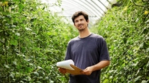 Retrato de un trabajador agrícola sonriente sosteniendo un portapapeles. El granjero está analizando documentos. Él está trabajando en invernadero. Retrato de un trabajador agrícola sonriente sosteniendo un portapapeles. El granjero está analizando documentos. Él está trabajando en invernadero.