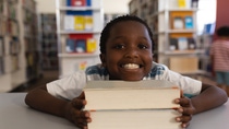 Happy schoolboy leaning his face on books and looking at camera Happy schoolboy leaning his face on books and looking at camera