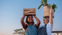 Two women farmers carrying baskets of crops