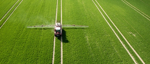 Aerial view of the tractor spraying the chemicals on the large green field Aerial view of the tractor spraying the chemicals on the large green field