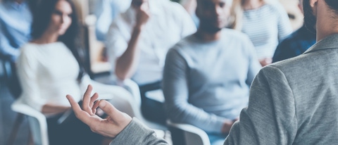 Business coach. Rear view of man gesturing with hand while standing against defocused group of people sitting at the chairs in front of him ; Shutterstock ID 439214011; Jobnummer: 02200; Projekt: PrÃ¤sentation; Endkunde: BASF SE, G-EVO/EB, Frau Sauer; Sonstiges: BASF SE, ESI/K Matthias Baque