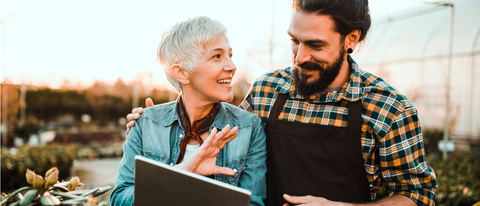 A man and woman are standing in a nursery, watching at a tablet A man and woman are standing in a nursery, watching at a tablet