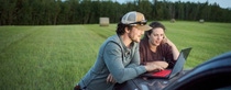 Young farmer couple looking at a laptop on pick-up truck hood while working on a farm