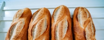 Four loaves of bread stand vertical on a white shelf.