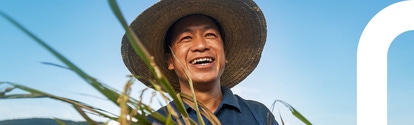 Farmer smiling while holding a harvested rice plant