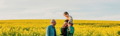 Un padre lleva a su hijo al hombro junto a su abuelo en un campo de colza Un padre lleva a su hijo al hombro junto a su abuelo en un campo de colza