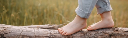 Child balancing on a trunk lying in front of a field