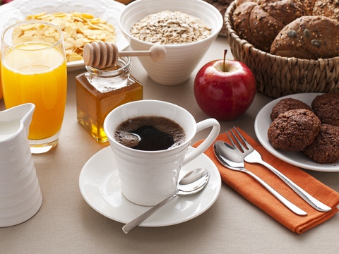 Combine harvesting oilseed rape in the middle of a large field surrounded by nature during late summer or autumn.