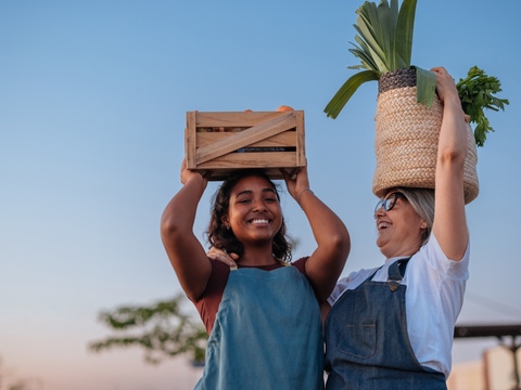 Two women farmers carrying baskets of crops