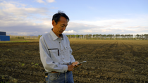 A farmer with a smartphone standing on an acre