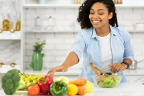 Casual girl preparing healthy lunch for her family in modern kitchen, taking vegetables.
